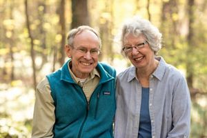 A smiling couple in a sunny wooded setting